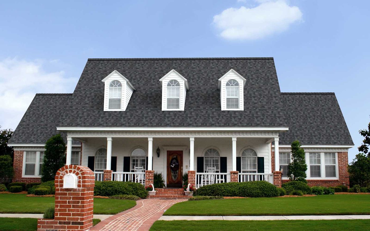 The same white farmhouse with red brick accents roofed in Owens Corning TruDefinition Duration shingles in Williamsburg Gray