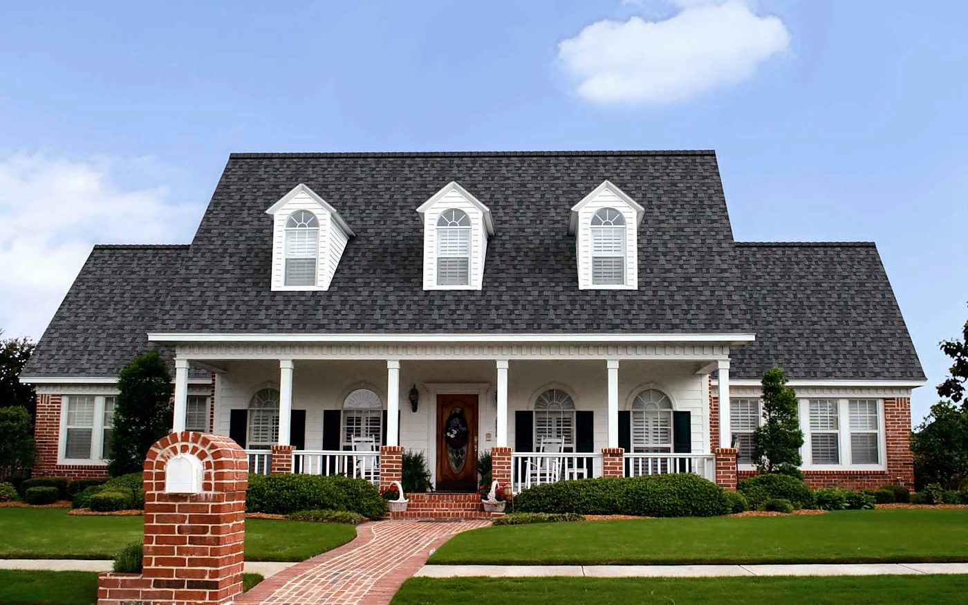The same white farmhouse with red brick accents roofed in Owens Corning TruDefinition Duration shingles in Williamsburg Gray