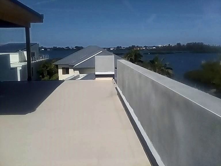 Walkable membrane roof deck with a parapet wall on a waterfront home