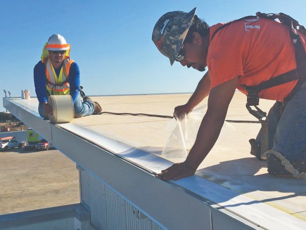 Crew installing a Carlisle PVC cover strip along a commercial roof edge