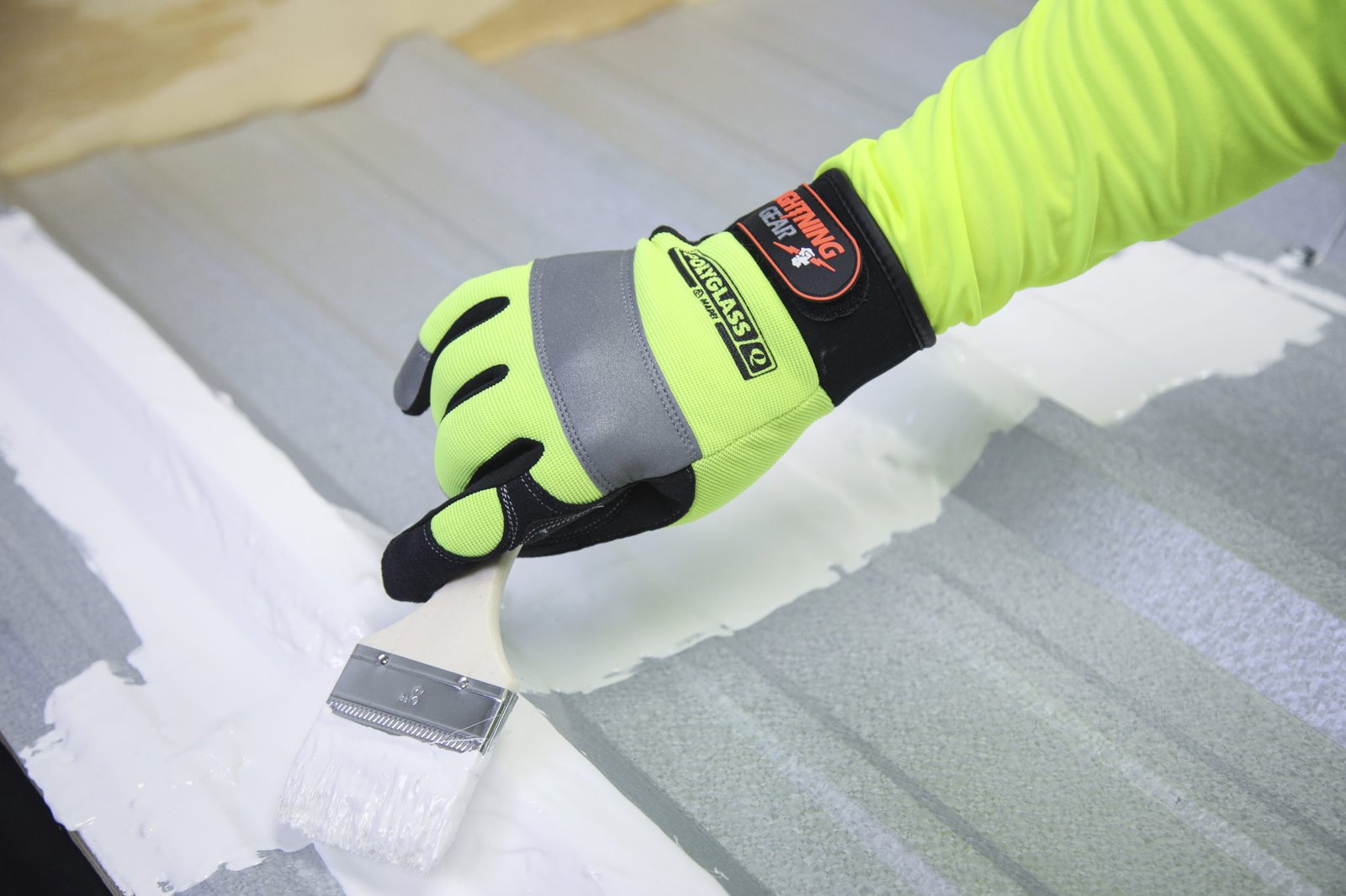 Roofer brushing a Polyglass coating onto a metal roof seam
