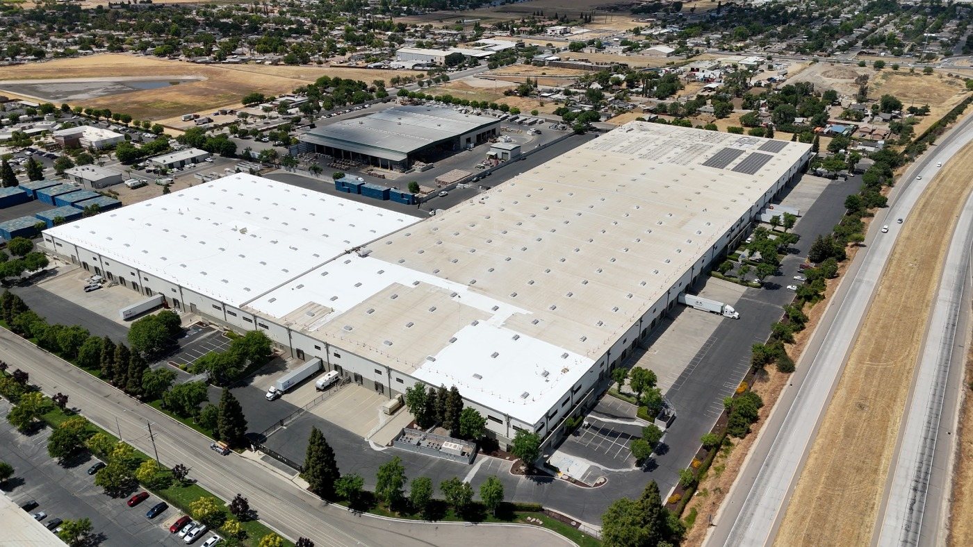 Aerial of a large logistics warehouse with a reflective white coated roof