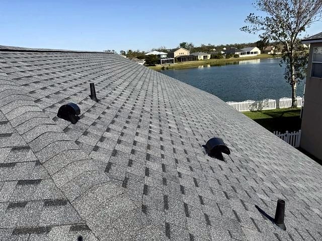 Pewter gray shingle roof with roof vents beside a lake