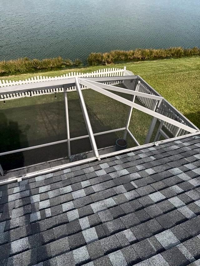 Gray shingle roof beside a screened pool enclosure overlooking a lake