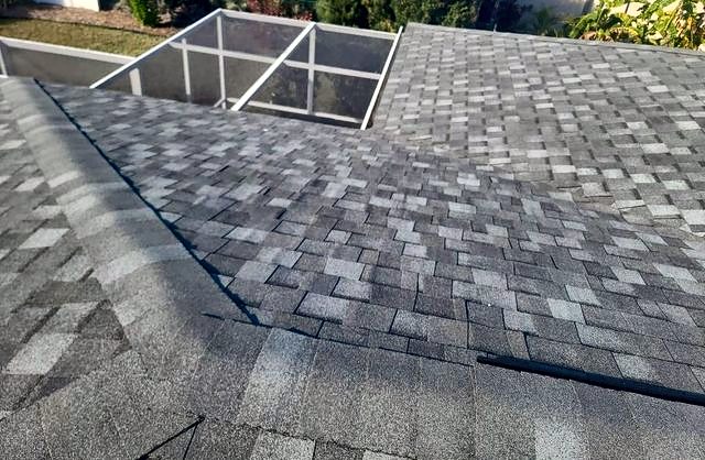 Gray-blue shingle roof valley next to a screened pool enclosure