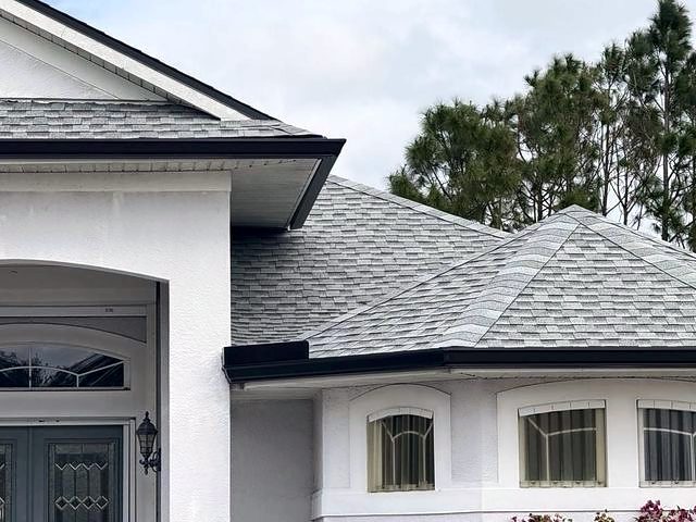 Light gray shingle roof over a white stucco home with an arched entry