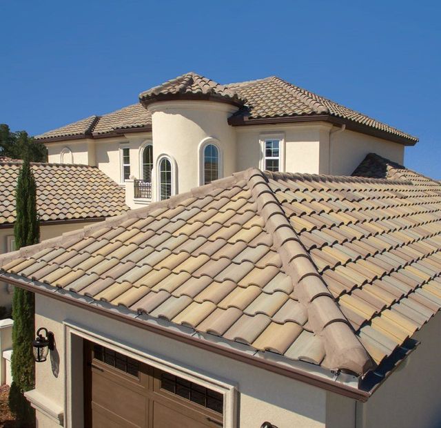 Tan blended barrel concrete tile roof over a garage with a two-story home behind