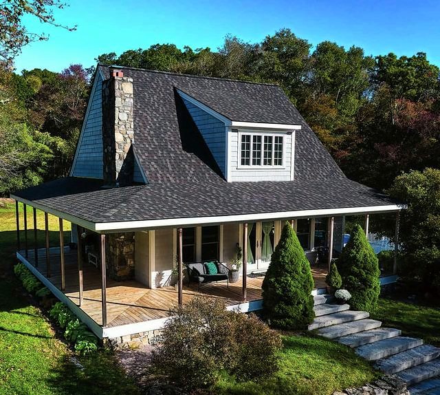 Craftsman-style home with a dark architectural shingle roof and a wraparound porch
