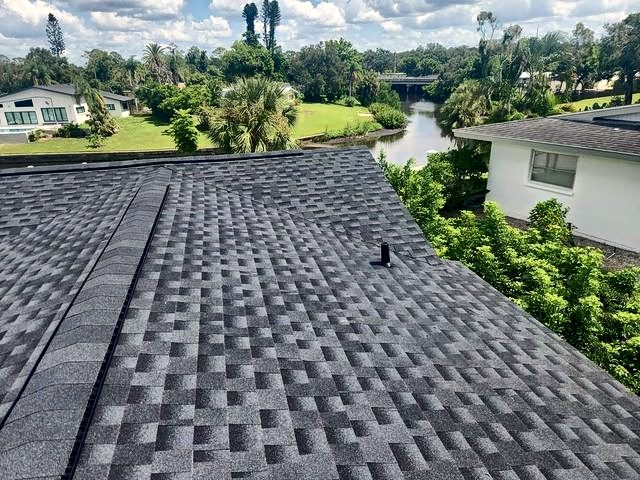 Dark charcoal shingle roof with a canal and palms beyond